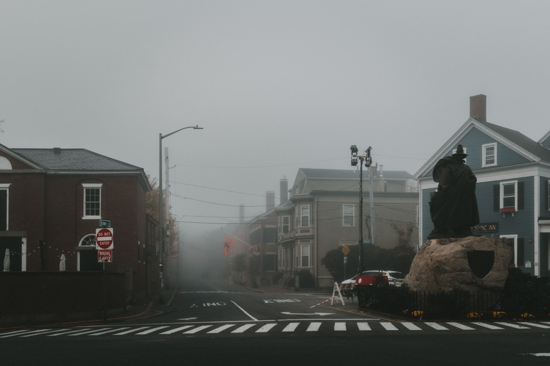 Foggy morning street scene in Salem, Massachusetts with a statue