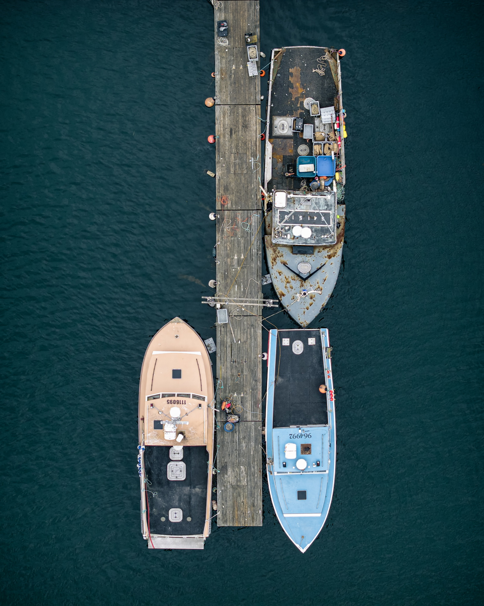 Aerial photograph of three working boats moored at a narrow dock in Beverly Harbor Massachusetts