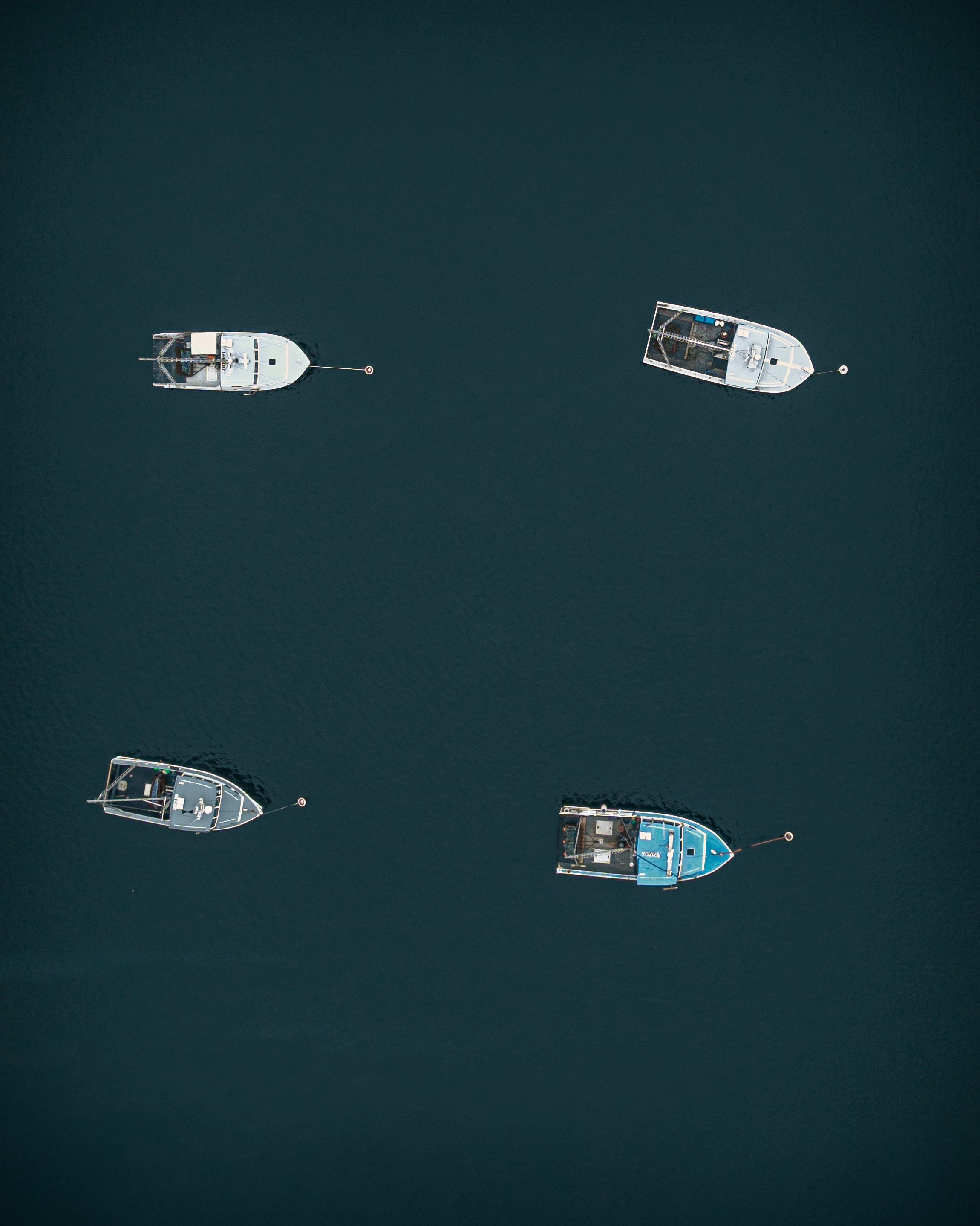 Aerial overhead photograph of five scallop draggers moored in Gloucester Harbor Massachusetts including one with green fishing gear on deck